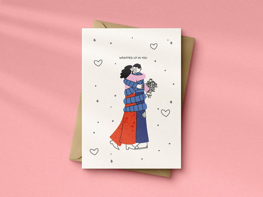 Greeting card with illustration of two people wrapped in each other on a pink background