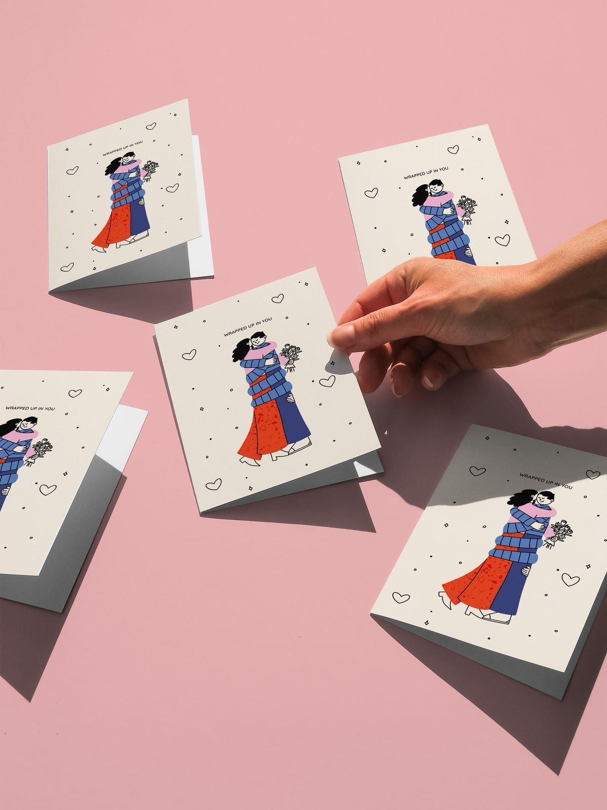 Hand holding a card with illustrations of people on a pink background