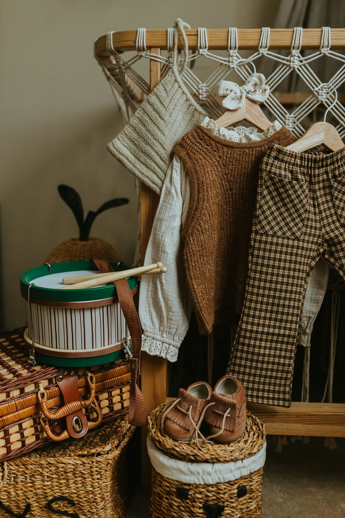 Children's clothes on a rattan rail with baskets and small leather shoes